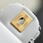 Chanel logo gold plate on white textured bag flap with snap closure