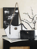 Two-tone Chanel tote bag with gold chain handles, black trim, and CC logo