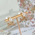 Gold-tone bar earrings with bow charms and pearl beads, crystal accents