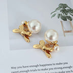 Gold-tone drop earrings with bow charm and pearl bead accents
