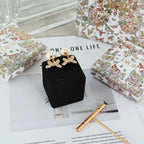 Dior floral bow earrings set with pearl drops displayed on black pouch