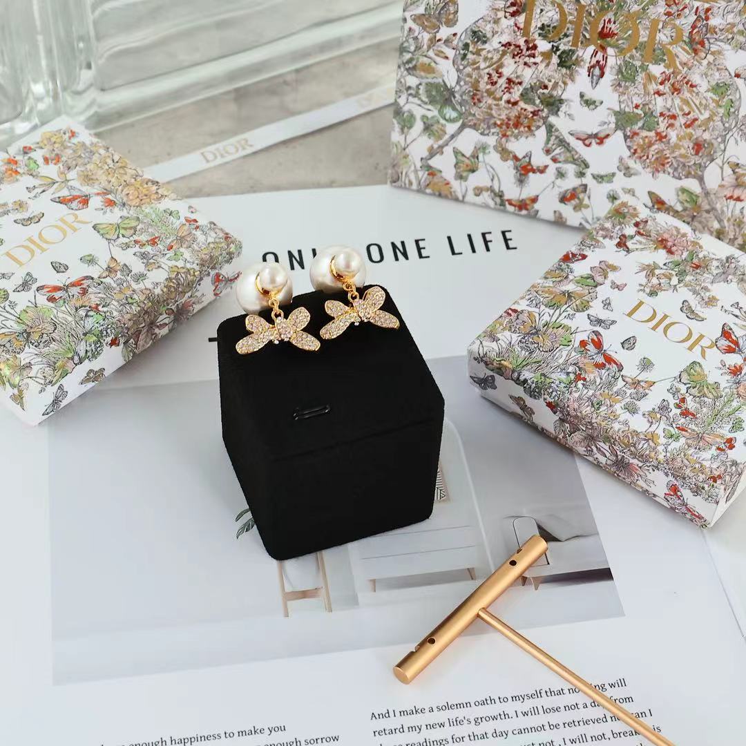 Dior floral bow earrings set with pearl drops displayed on black pouch