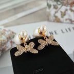 Gold-tone bow earrings with clear crystal details and pearl drop