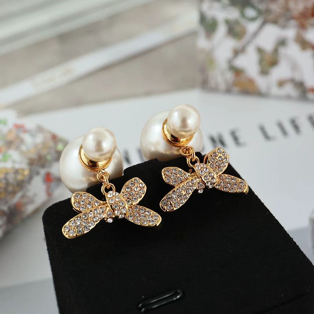 Gold-tone bow earrings with clear crystal details and pearl drop
