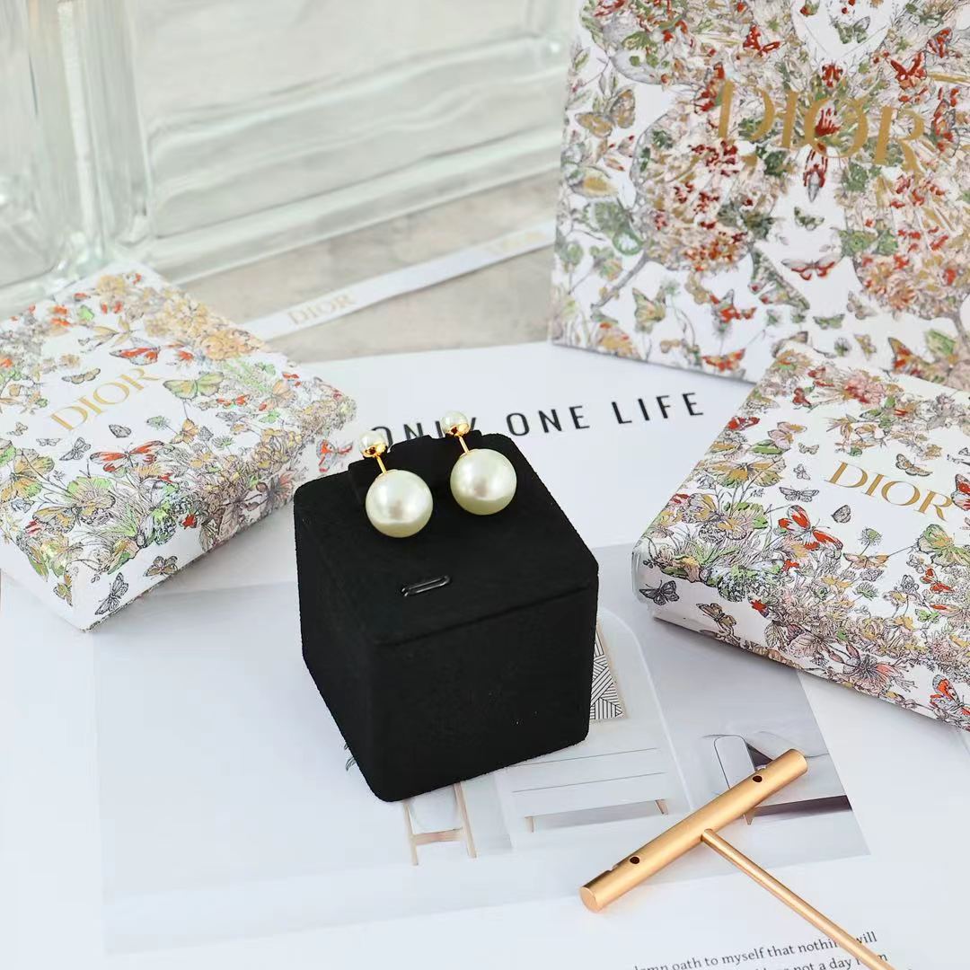 Pair of pearl drop earrings with gold-tone posts, shown on a black presentation box.