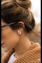 Woman wearing pearl drop earrings with small round pearls near the ear and gold posts.