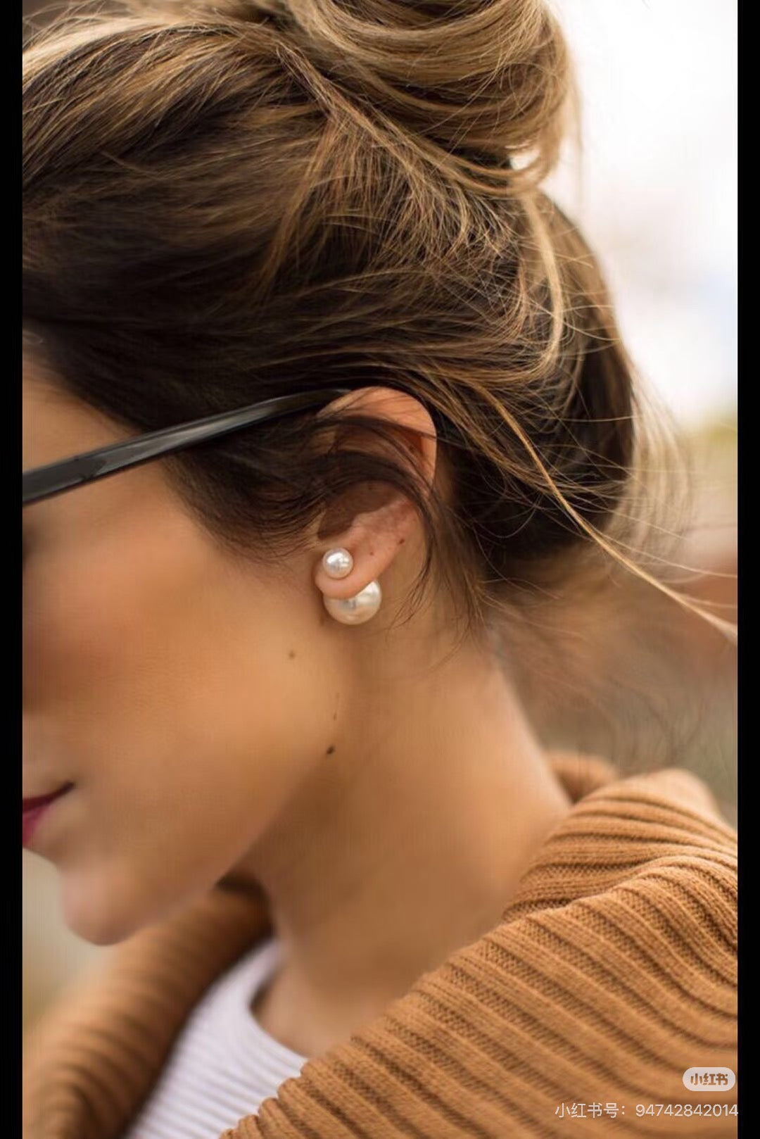 Woman wearing pearl drop earrings with small round pearls near the ear and gold posts.