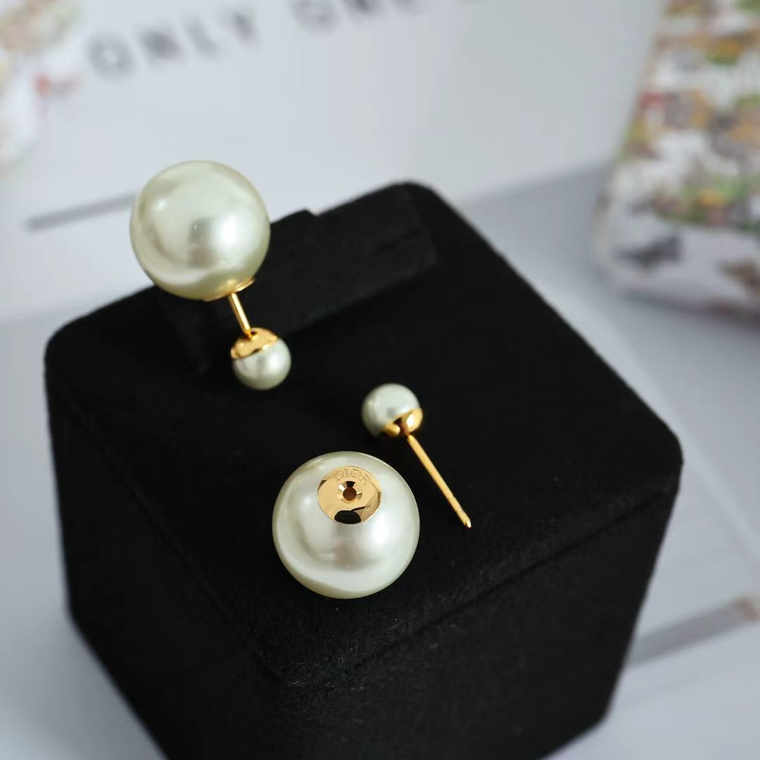 Gold-tone pearl drop earrings with circular pearl studs and posts on display.