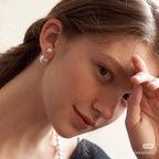 Woman wearing small pearl earrings with a gold-tone hoop and clustered pearl details.