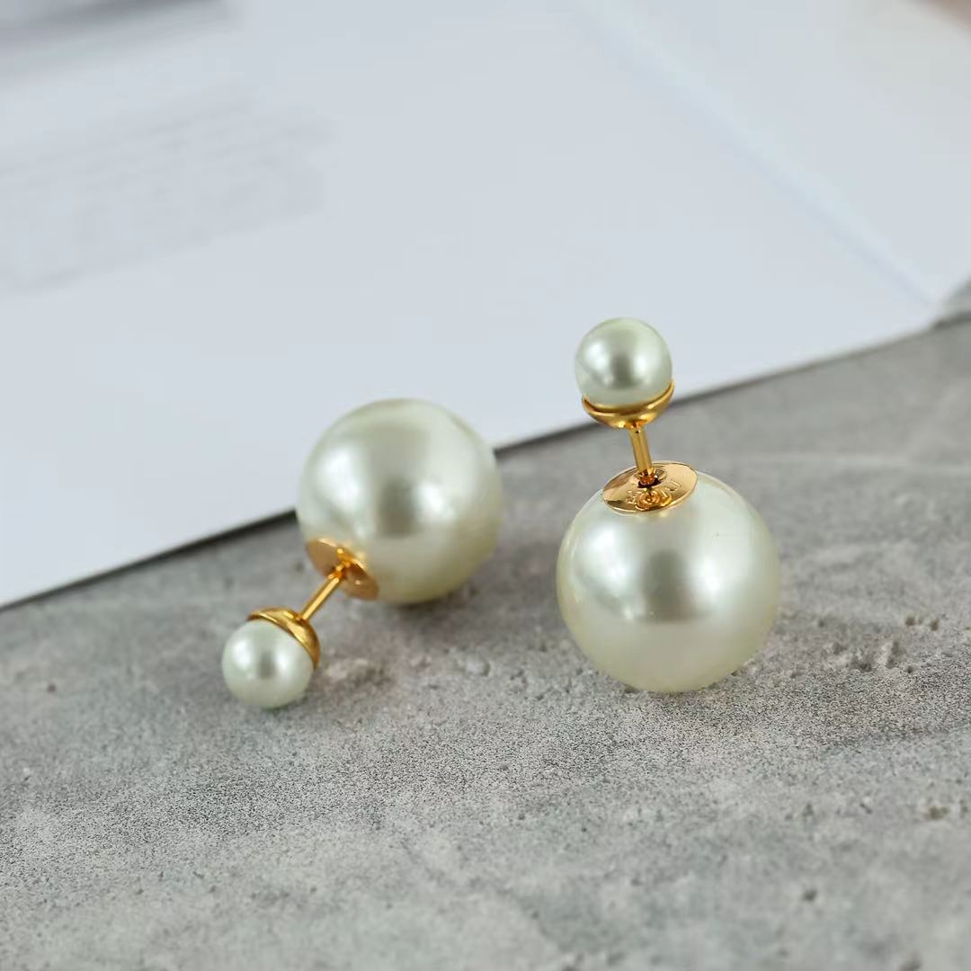Close-up of gold-tone pearl drop earrings with large round pearls and small pearl accents.