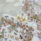Pearl drop earrings on a Dior accessory box, featuring gold-tone fittings and white pearls.