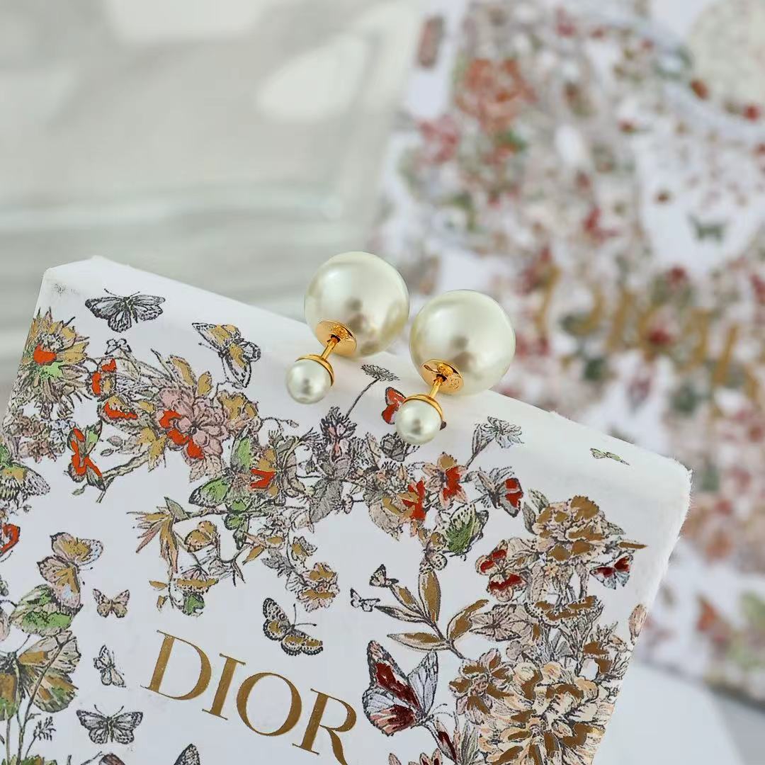 Pearl drop earrings on a Dior accessory box, featuring gold-tone fittings and white pearls.