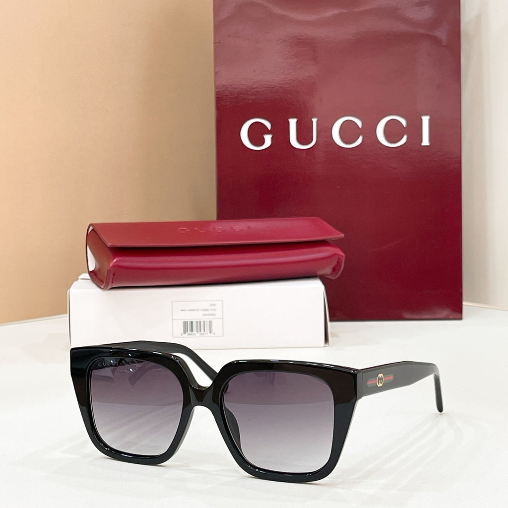Black square sunglasses with dark tinted lenses and gold logo on the temple arm