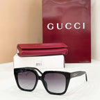 Black square sunglasses with dark tinted lenses and gold logo on the temple arm