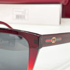 Burgundy sunglasses temple with gold logo accent and dark tinted lens edge