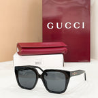Black square sunglasses with dark tinted lenses and gold logo on the temple arm