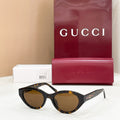 Black cat-eye sunglasses with dark lenses, Gucci logo on temples and gold accents.