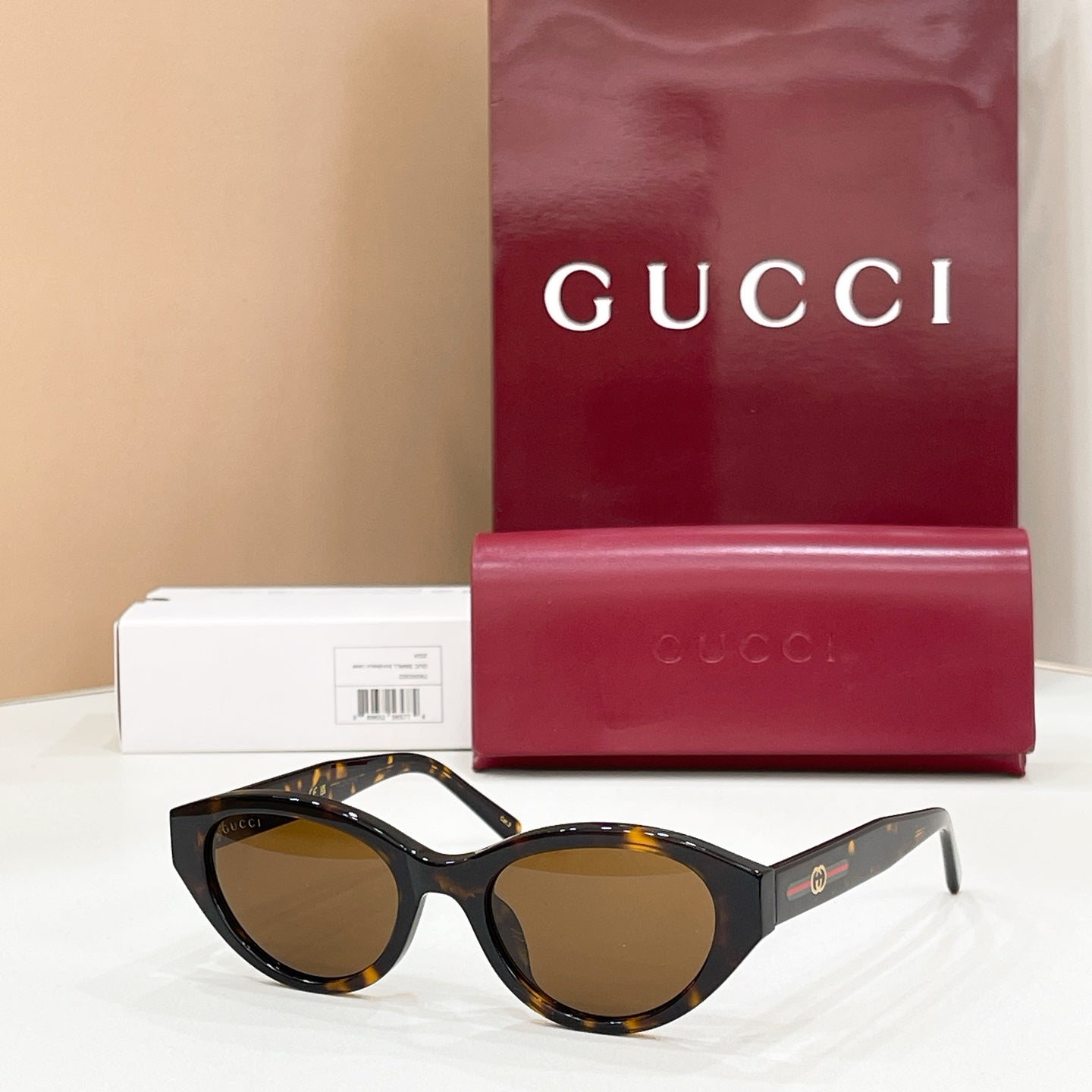 Black cat-eye sunglasses with dark lenses, Gucci logo on temples and gold accents.