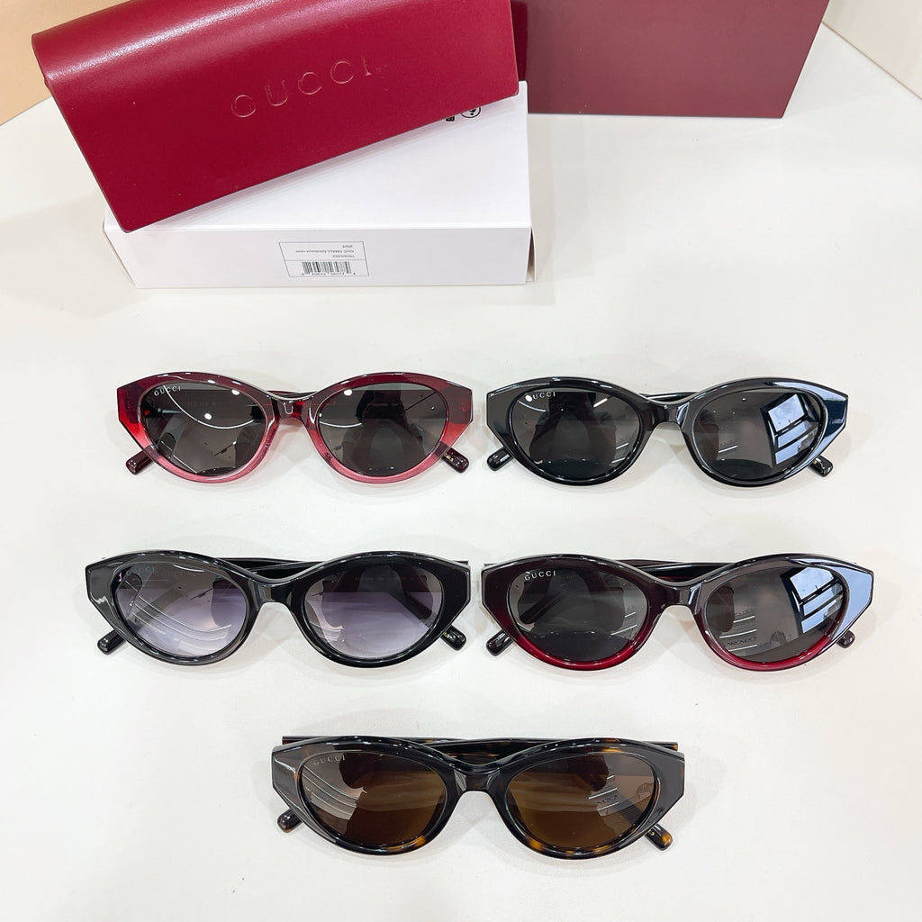 Assorted Gucci sunglasses on white surface, black and red frames with dark lenses.