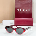 Black sunglasses with red-tinted arms and dark lenses, Gucci logo on temple ends.