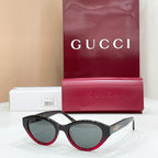 Black sunglasses with red-trim edges and dark lenses, Gucci logo on temples.