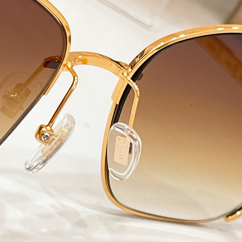 Gold-tone sunglasses close-up of hinge and arms with amber tinted lenses