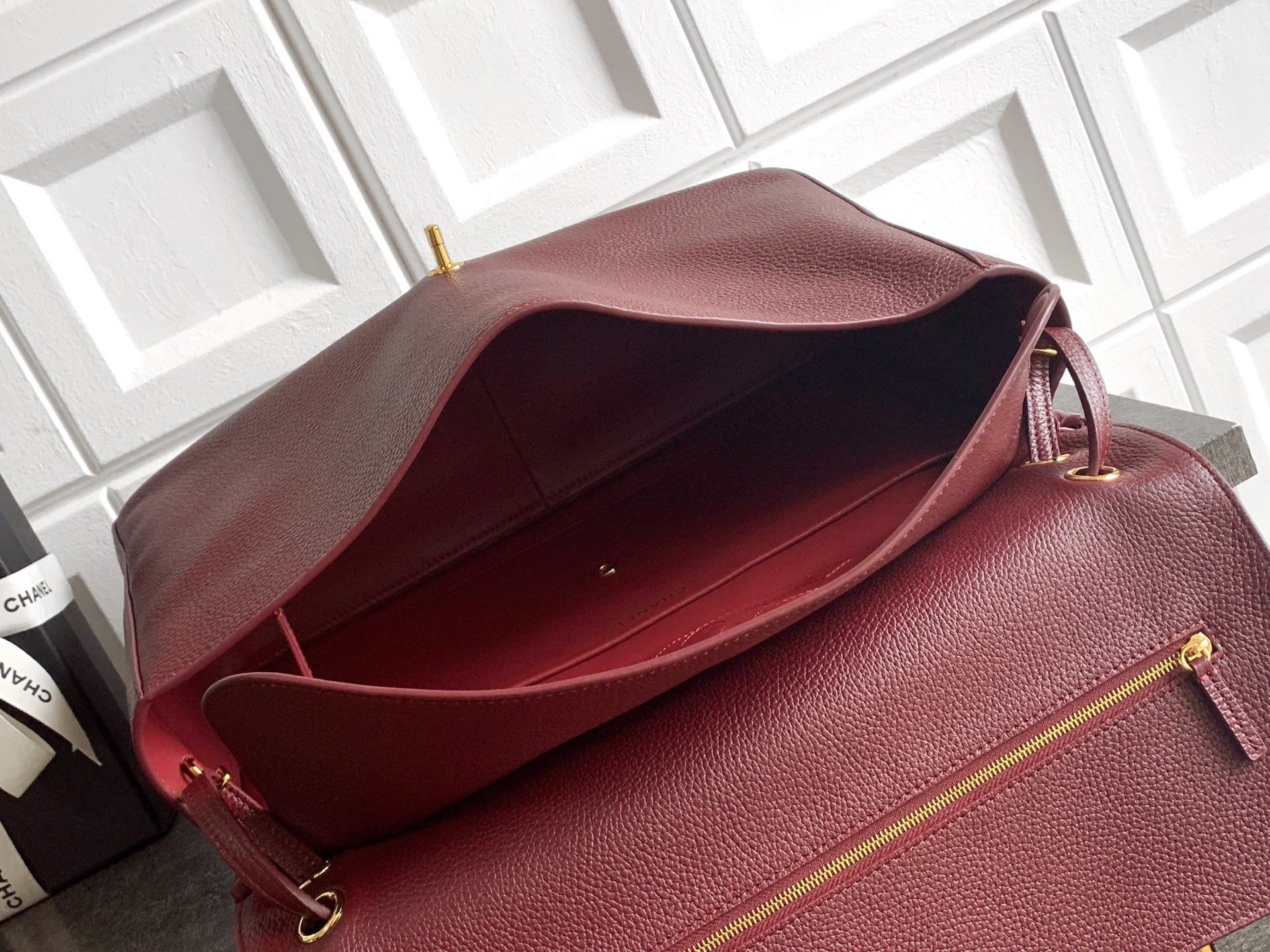 Burgundy leather bag with open top and gold-tone zip pocket