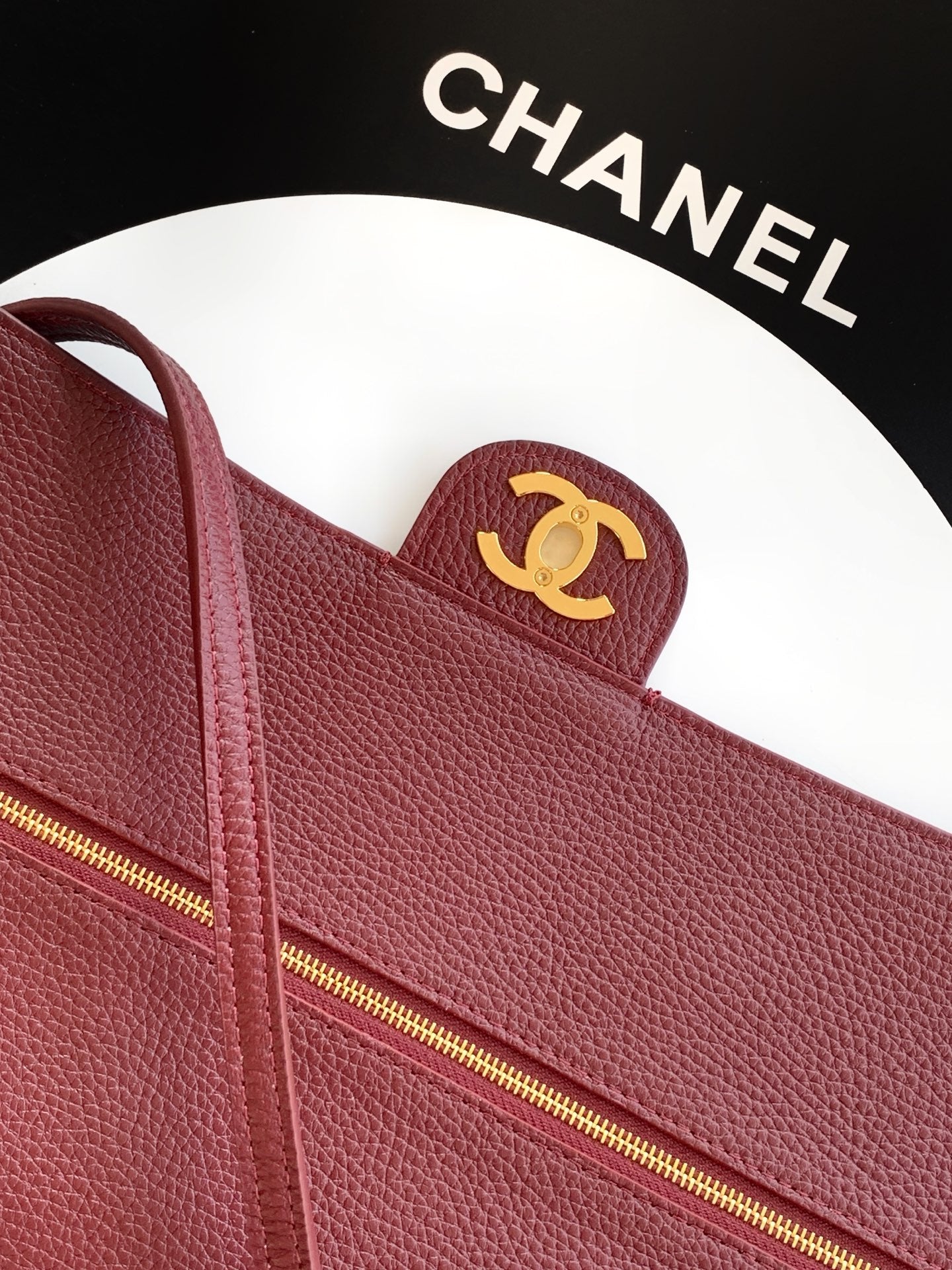 Burgundy leather handbag with gold-tone zip and small Chanel CC badge