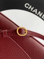 Burgundy leather bag strap with gold-tone buckle and fastening holes