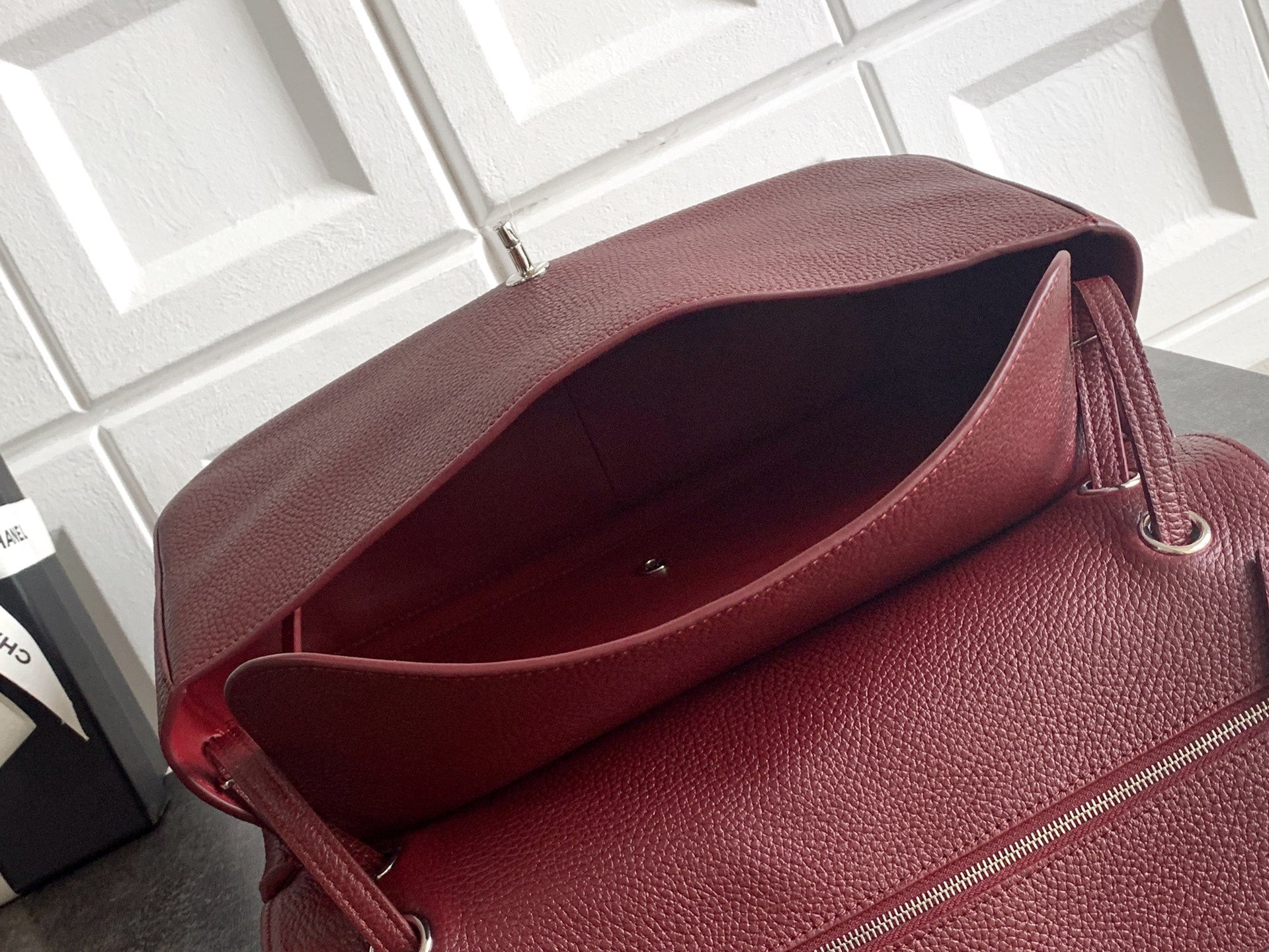 Burgundy Chanel bag with open flap showing dark interior lining.