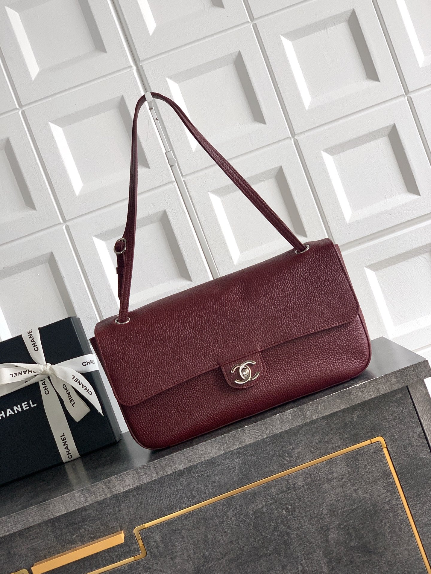 Burgundy Chanel flap shoulder bag with gold-tone CC clasp and top handle.