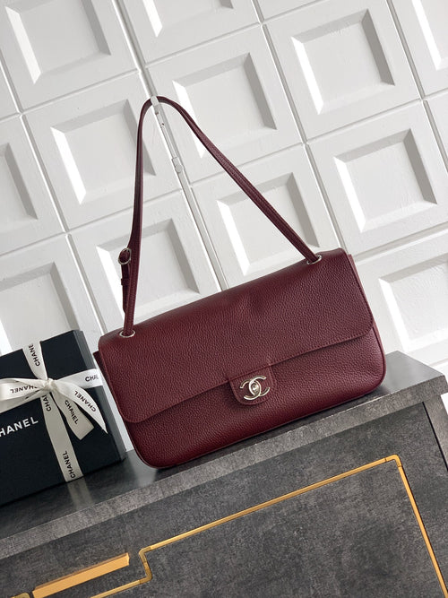 Burgundy Chanel flap shoulder bag with gold-tone CC clasp and top handle.
