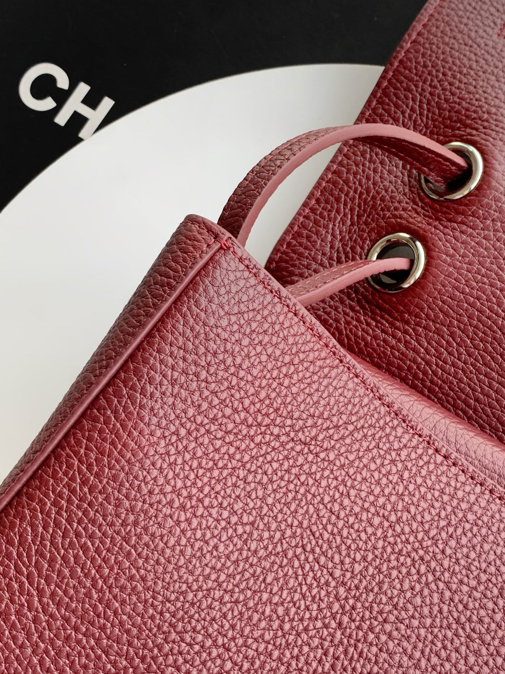 Burgundy Chanel bag with textured leather and gold-tone O-ring strap hardware.