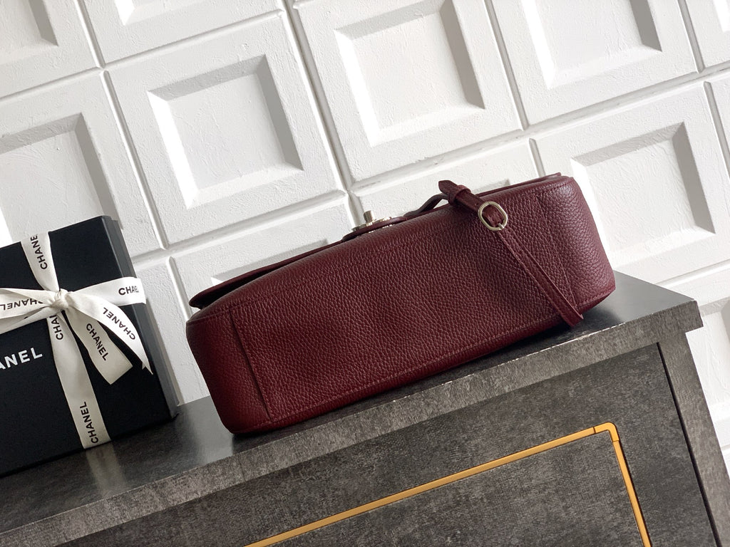 Burgundy Chanel long clutch-style bag with shoulder strap and loop closure hardware.