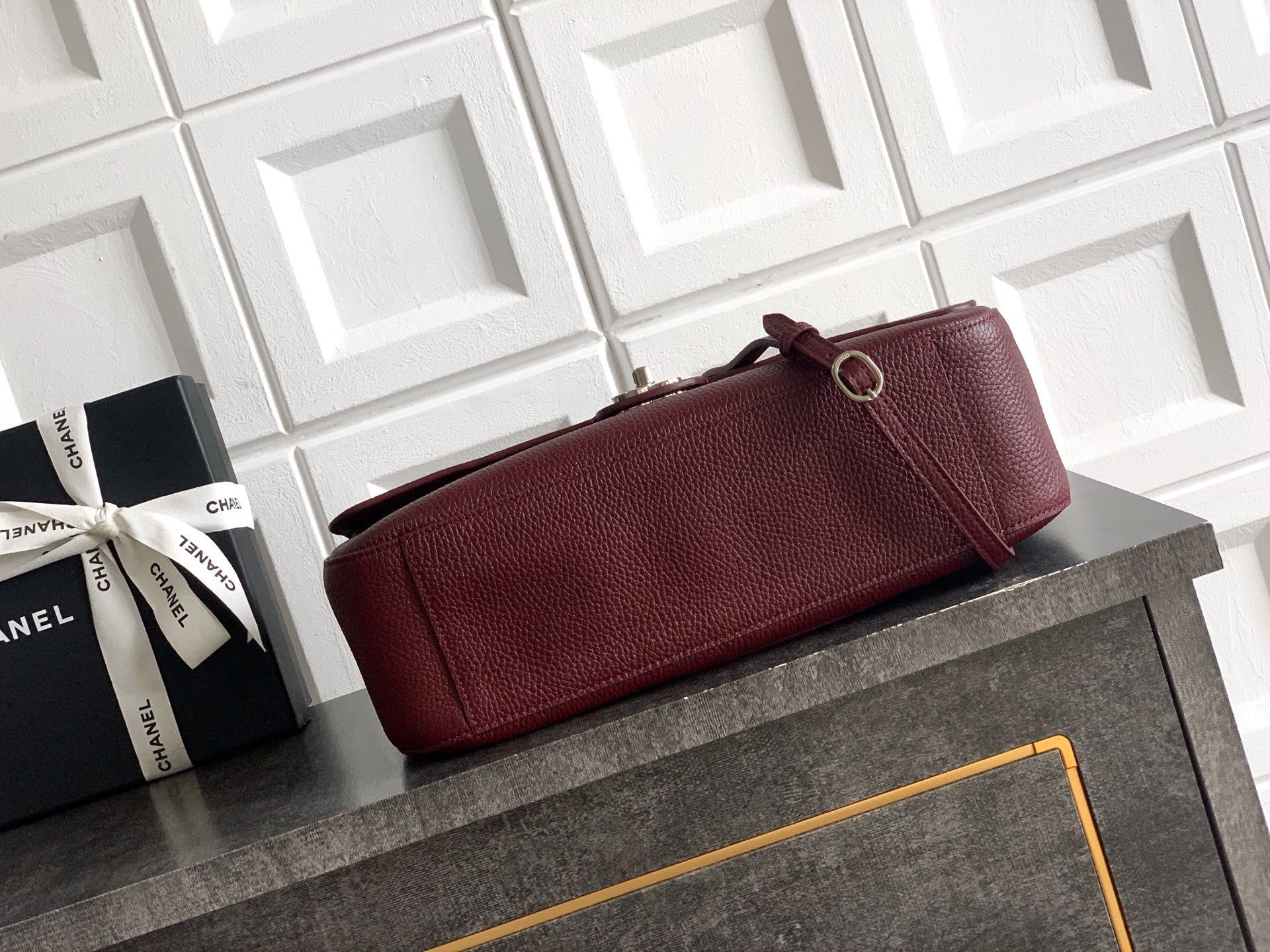 Burgundy Chanel long clutch-style bag with shoulder strap and loop closure hardware.
