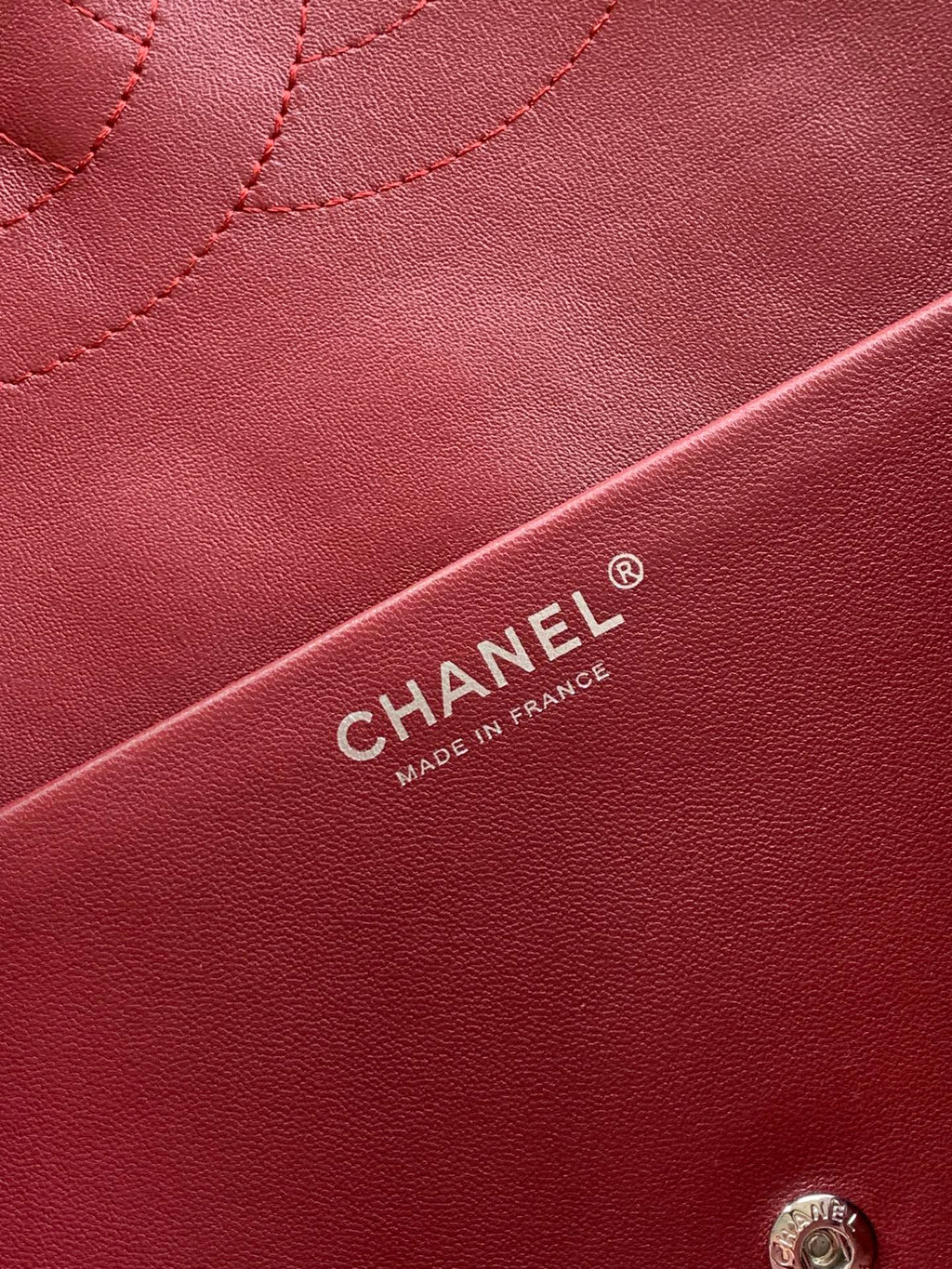 Chanel bag leather close-up in maroon with CHANEL® label and stitching detail