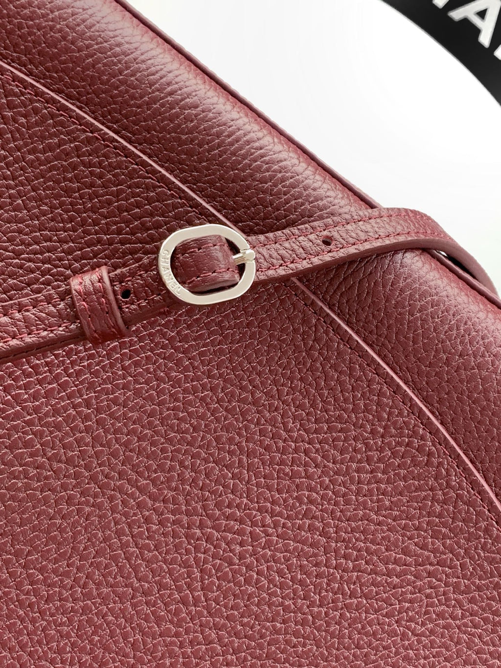Chanel bag close-up: maroon textured leather with metal ring and front handle loop