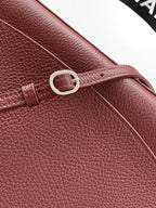 Chanel bag close-up: maroon textured leather with metal ring and front handle loop