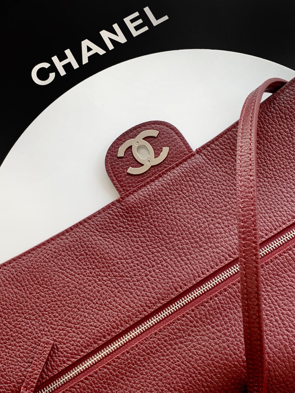 Chanel bag close-up: maroon textured leather with zipper and interlocking CC logo