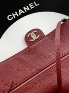 Chanel bag close-up: maroon textured leather with zipper and interlocking CC logo