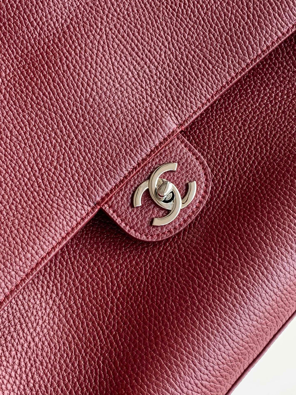 Chanel bag detail: maroon textured leather flap with silver-tone interlocking logo