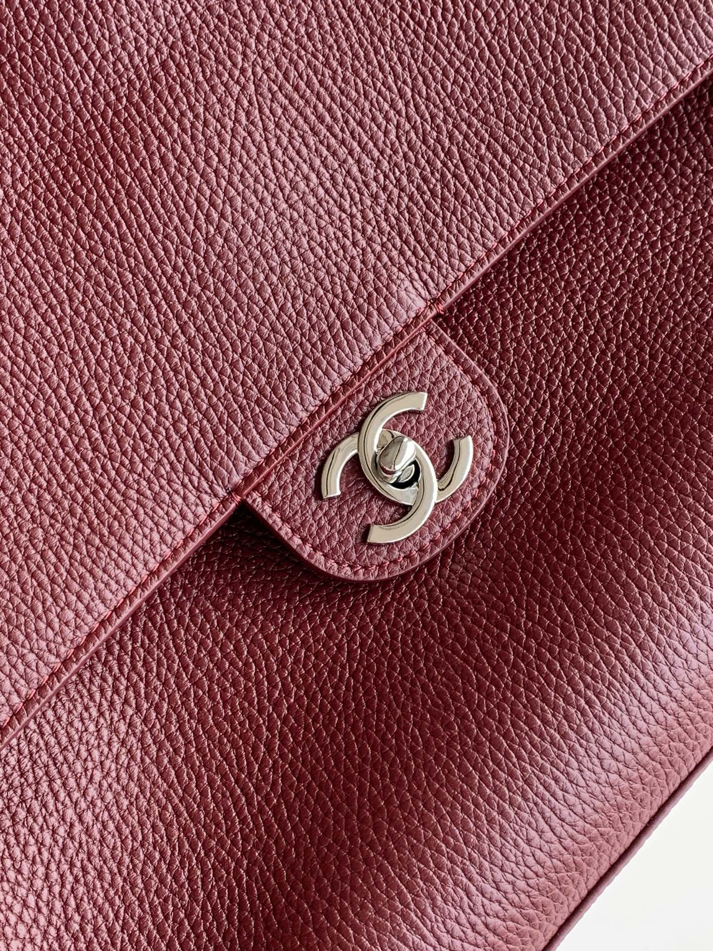 Chanel bag detail: maroon textured leather flap with silver-tone interlocking logo