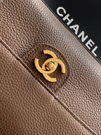 Chanel bag close-up of gold logo turn-lock on textured taupe leather
