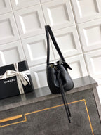 Black Chanel handbag with long strap and side flap, front-angle view