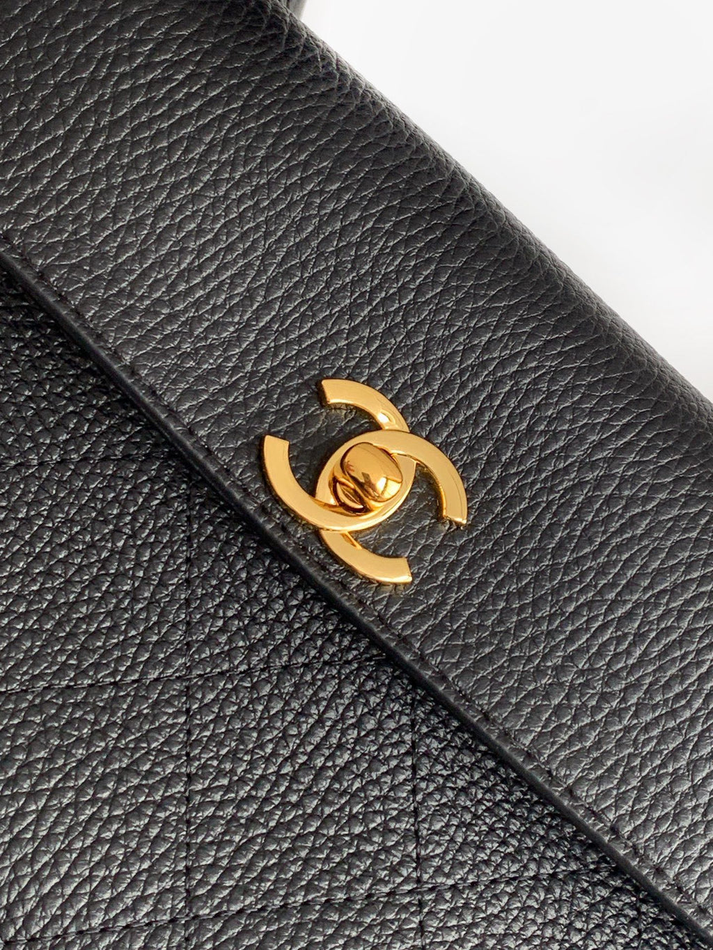 Black textured leather flap with gold Chanel turn-lock clasp