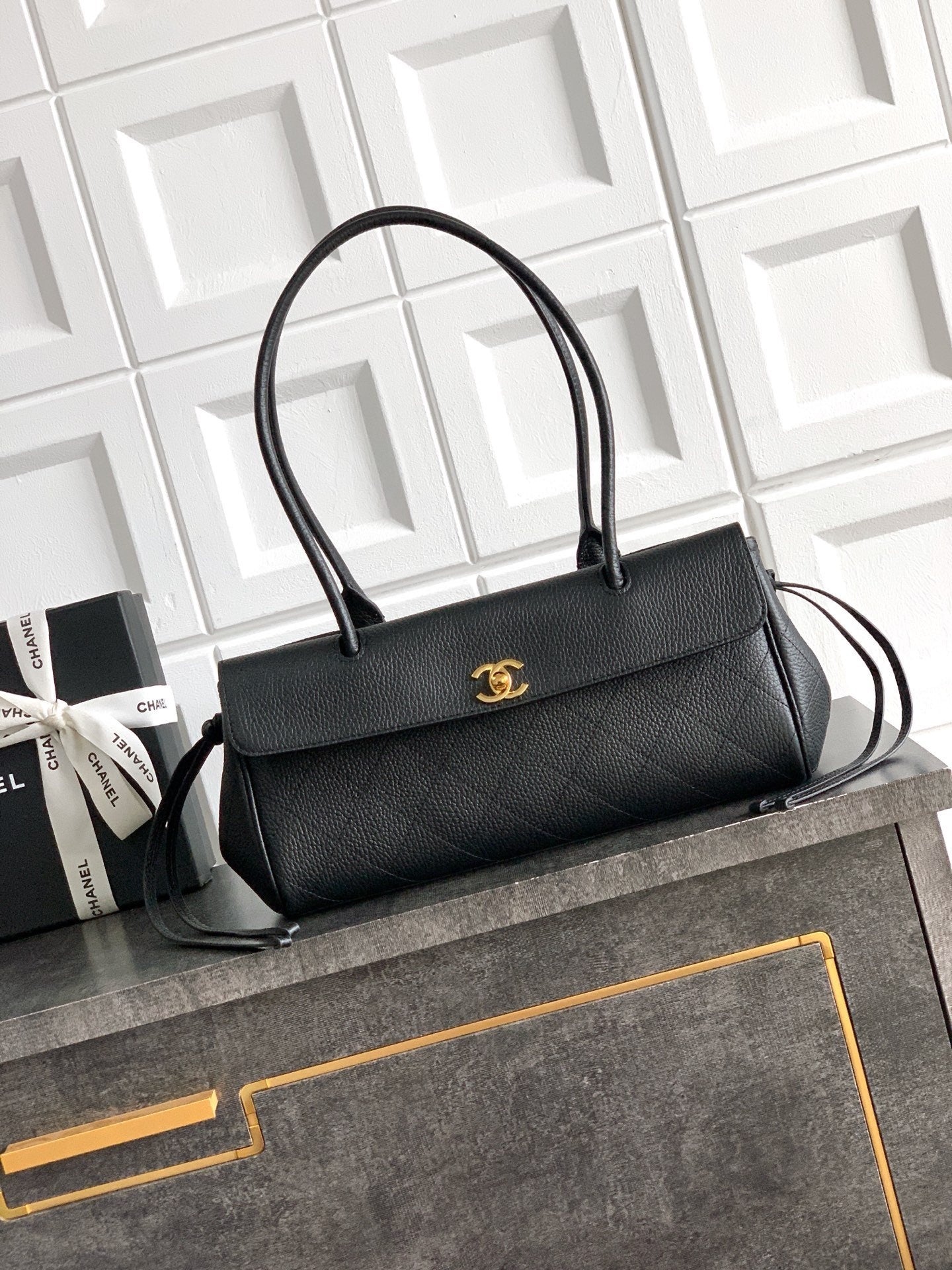 Black Chanel top-handle bag with gold logo plate on the front