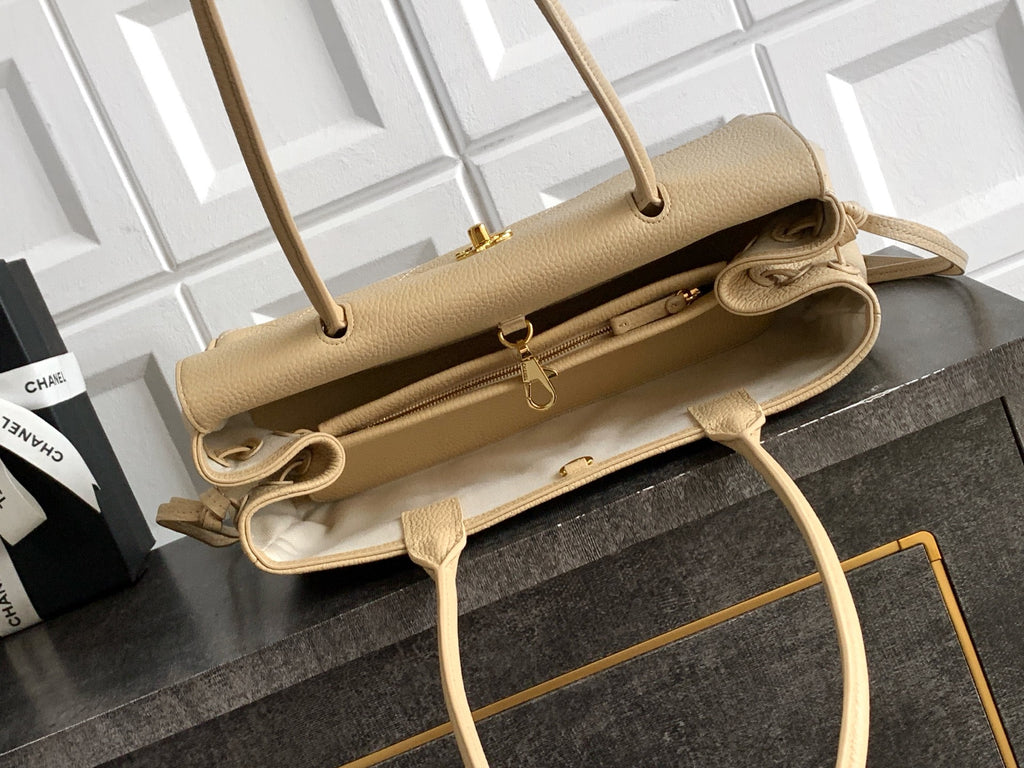 Beige Chanel leather handbag opened to show interior, top handles and adjustable strap