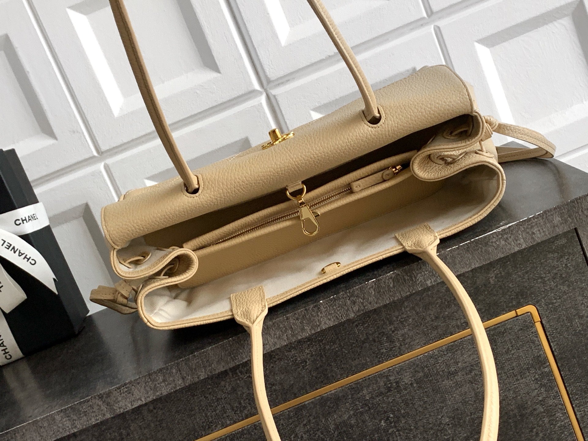 Beige Chanel leather handbag opened to show interior, top handles and adjustable strap