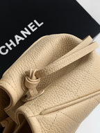 Beige pebbled leather Chanel bag close-up with twisted drawcord strap detail
