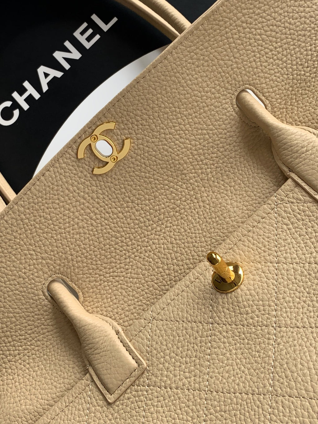 Beige pebbled Chanel leather bag front with gold CC hardware and strap tab